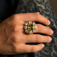 Bague Magnolia dorée portée sur le majeur, vue de dessus, sur une main posée sur un tissu à motif léopard